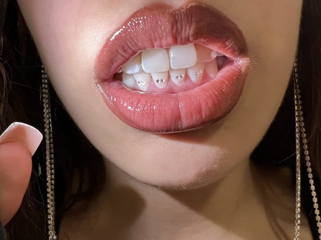 Mujer sonriente aplicando una máscara de ojos de piedra negra sobre su rostro.